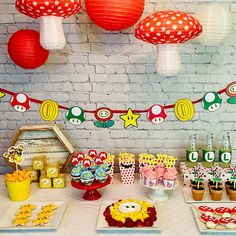 a table topped with cupcakes and cakes next to paper lanterns hanging from the ceiling