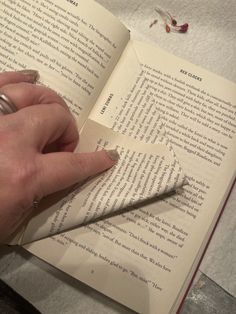 a person is reading a book with their hand on the page and writing something in it