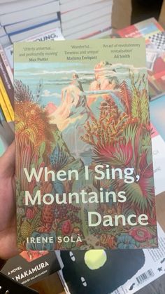 someone holding up a book in their hand with the title when i sing mountains dance