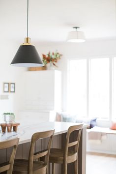 a kitchen island with four chairs and a light fixture hanging over it's top