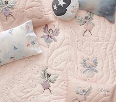 a pink bed with fairy themed sheets and pillows