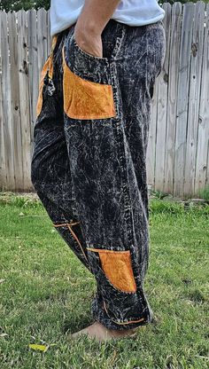 a man standing in the grass with his hands on his hips wearing jeans and sandals