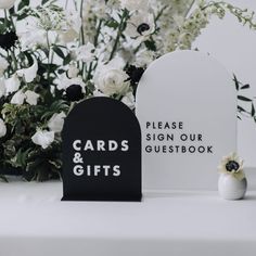 two cards and gifts sitting on a table with flowers in front of them, next to each other