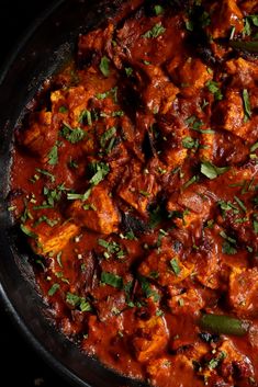 a pan filled with meat and vegetables covered in sauce