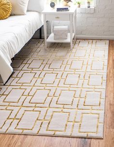 a white and gold rug in a living room next to a couch with pillows on it