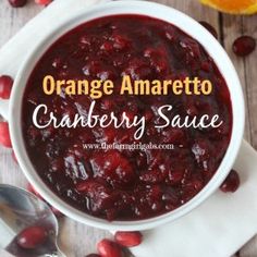 an orange and cranberry sauce in a white bowl with spoons next to it