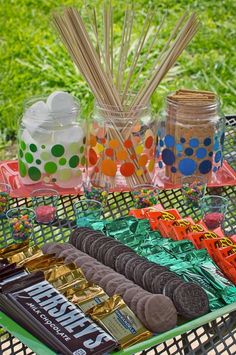 an assortment of cookies, candy bars and marshmallows on a picnic table