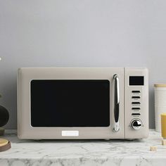 a white microwave oven sitting on top of a counter next to cups and vases