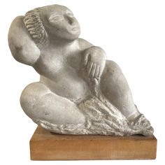 a white statue sitting on top of a wooden block