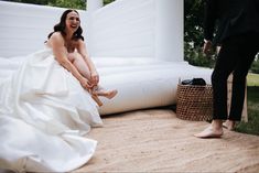 a woman in a white dress sitting on the ground next to a man wearing a suit