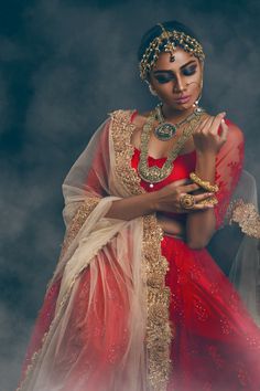 a woman in a red and gold outfit with jewelry on her neck, wearing a headpiece