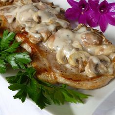 a white plate topped with meat covered in gravy next to a purple flower