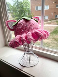 a pink crocheted hat sitting on top of a window sill