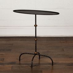 an iron table with a glass top on a wooden floor