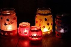 four jars with candles lit up in the dark