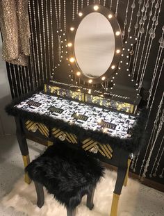 a vanity with a mirror, stool and lights on it in front of a curtained wall