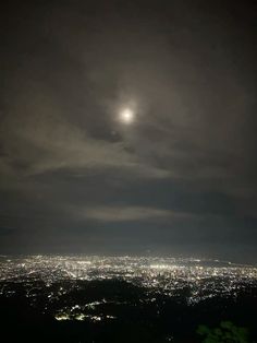 the city lights are lit up in the dark night sky as seen from atop a hill