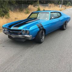 a blue muscle car parked on the side of the road