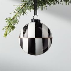 a black and white striped ornament hanging from a christmas tree with pine branches