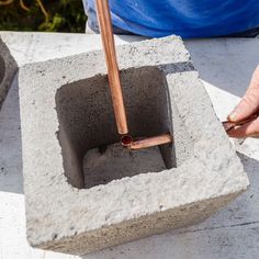 a person is working on a cement block with a pipe sticking out of the end