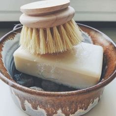 a wooden brush sitting on top of a bowl filled with soap and scrubbings