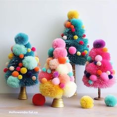 three brightly colored christmas trees with pom poms on them and balls in the middle