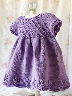 a purple knitted dress sitting on top of a wooden stand