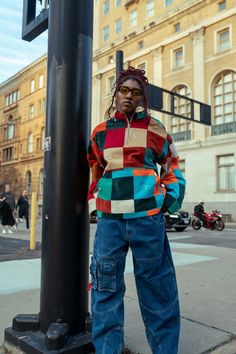 a person standing next to a pole on the street