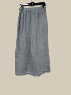 Indulge in luxury with these Button Detail Linen Pants. Made from premium Italian linen, these pants feature sophisticated button detailing, a flattering wide leg, and an elastic waist with drawstring for the perfect fit. With two front pockets and a distressed hem, these pants offer both style and comfort, making them a must-have for any elegant and cabin chic wardrobe. One Size (fits S-L) Solid Color Pants With Buttons For Loungewear, Wide Leg Loungewear Pants With Button Closure, Loungewear Pants With Buttons, Button-detail Loungewear Pants, Relaxed Fit Wide Leg Pants With Button Closure, Relaxed Fit Loungewear Bottoms With Buttons, Gray Relaxed Fit Wide Leg Pants, Linen Trousers With Button Closure, Elegant Linen Pants With Button Closure