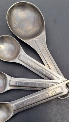 four spoons are sitting next to each other on a black table top with the words teaspoon biscuit written on them