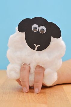 a hand holding a sheep made out of paper