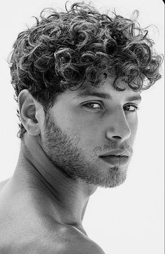 a shirtless man with curly hair and no shirt looking off to the side in black and white