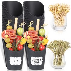 two black vases filled with different types of vegetables and fruits in them next to each other