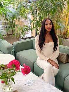 a woman sitting on top of a green couch next to a vase filled with flowers