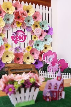 a table topped with lots of pink and yellow flowers next to a white picket fence