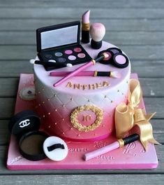 a birthday cake with makeup and cosmetics on it's top tier, sitting on a wooden table