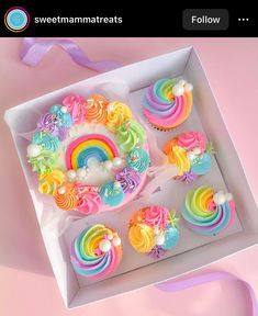 a box filled with cupcakes covered in rainbow icing