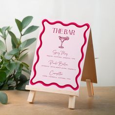 a pink sign sitting on top of a wooden table next to a potted plant