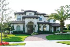 a large white house with palm trees in the front yard and landscaping on both sides