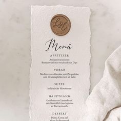 a menu card with a gold monogrammed circle on it and a white linen napkin