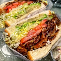 two sandwiches with meat, lettuce and tomatoes