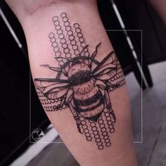 a black and white photo of a bee tattoo on the right leg with beads around it