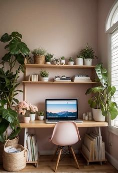 a laptop computer sitting on top of a wooden desk next to a potted plant