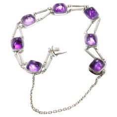 This rare and exquisite bracelet by renowned jewelry manufacturer, Theodor Fahrner is crafted in silver and set with sugarloaf cabochons of natural amethyst. Created in the early 1900s, this dainty yet powerful bracelet reflects the Jugendstil (the German version of Art Nouveau) ideal. Created entirely by hand, from natural materials. The 7 sugarloaf cabochons of natural amethyst gemstones measure approximately 8.30mm x 9.16mm with a depth of 5.07mm. When the bracelet is open, the safety chain remains connected and the opening provided measures approximately 8". Closed, the bracelet is approximately 6 ¾", so the bracelet will fit an individual with a smaller wrist. Jewelry created by Theodor Fahrner is highly collectible due to its historical significance, artistic integrity and unique des Jewelry Manufacturer, Bracelet In Silver, Modern Bracelets, Wrist Jewelry, Safety Chain, Jewelry Manufacturers, Early 1900s, Amethyst Gemstone, Silver Bracelets