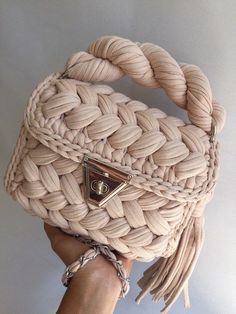 a hand holding a beige woven purse