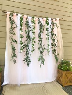 a white curtain with green plants hanging from it's sides and lights on the side