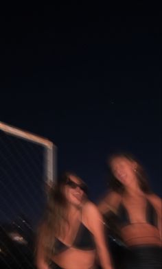 three women in bathing suits are posing for the camera with a volleyball net behind them