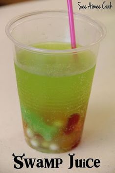 a green drink with a pink straw sitting on top of a white counter next to the words swamp juice