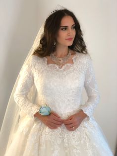 a woman in a white wedding dress with a blue flower on her belt and veil