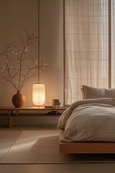 a bed sitting in a bedroom next to a table with a lamp on top of it